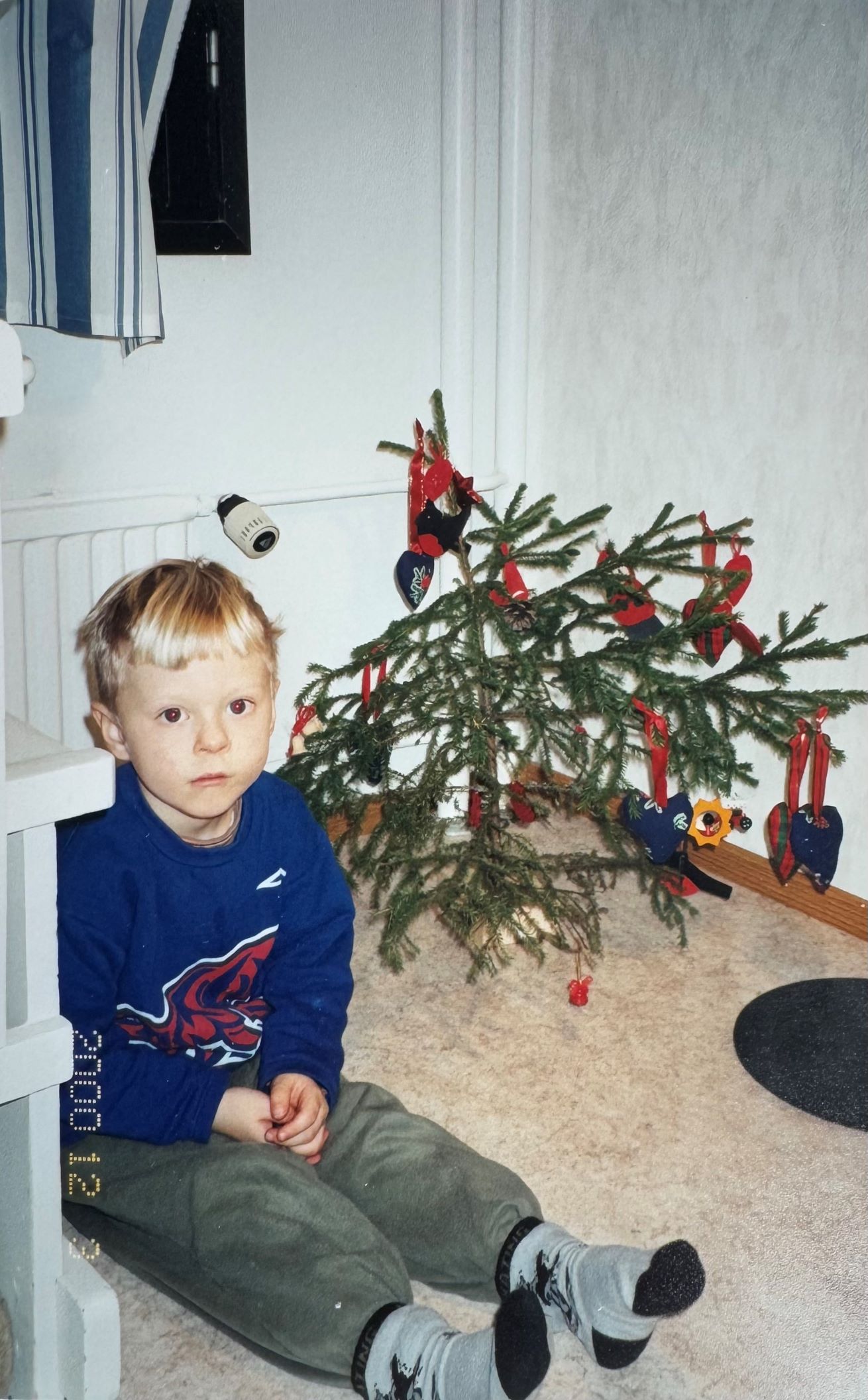 Atte Kilpinen istuu lapsena joulukuusen edessä.